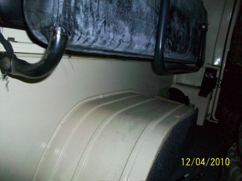 1986 Jeep Wagoneer - The interior of a vehicle shows a wheel well and exhaust system, with visible date and website information in the corner.