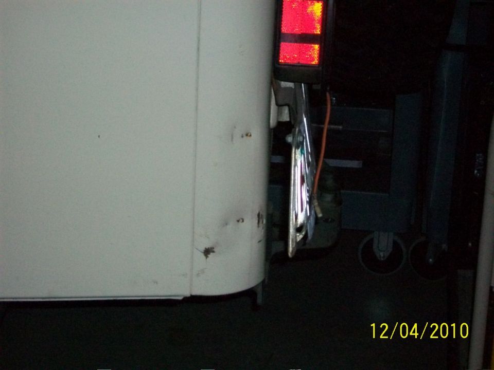 White vehicle's rear corner showing a red rectangular taillight and chrome trim. Date stamp reads 12/04/2010