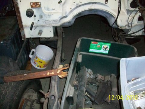 1986 Jeep Wagoneer - Close-up of vehicle chassis components and storage containers with parts.