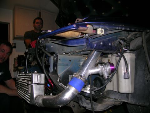 1995 Ford Probe - Custom turbocharger and intercooler system being installed in a blue vehicle's engine bay.