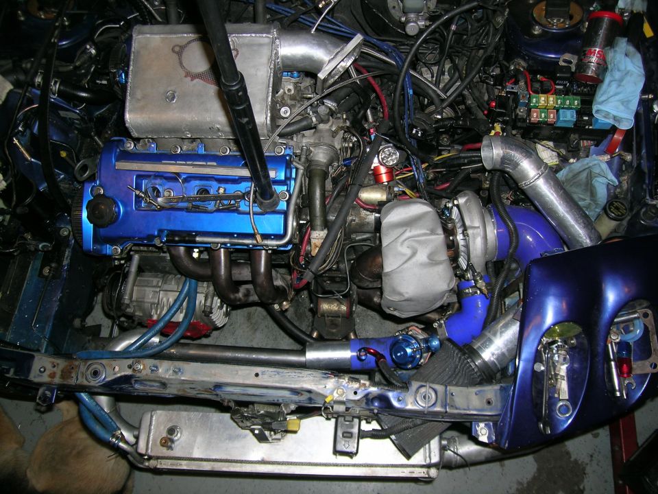 Engine bay with blue valve cover, turbocharger, intercooler piping, and wiring