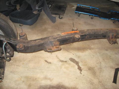 1963 Ford Galaxie - A rusted vehicle frame section is shown on a concrete floor with a tire and other parts in the background.