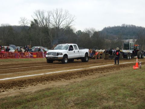 2007 Ford Mustang - A white 2007 Ford F-350 Super Duty pickup truck competes in a tractor pull event, with spectators watching from the sidelines.