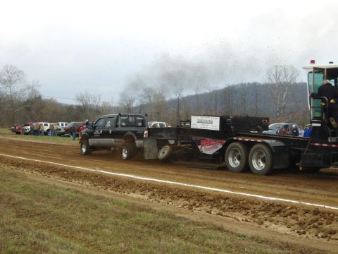 2007 Ford Mustang - A truck competes in a pulling event, kicking up dirt and smoke as it drags a heavy trailer.