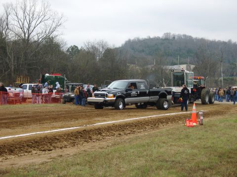 2007 Ford Mustang - A black Ford F-350 Super Duty pickup truck participates in a tractor pull event, with spectators gathered around.