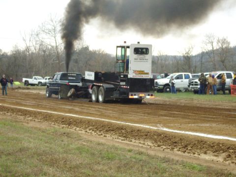 2007 Ford Mustang - A truck pulls a trailer with a tractor unit, kicking up black smoke during a pull event.