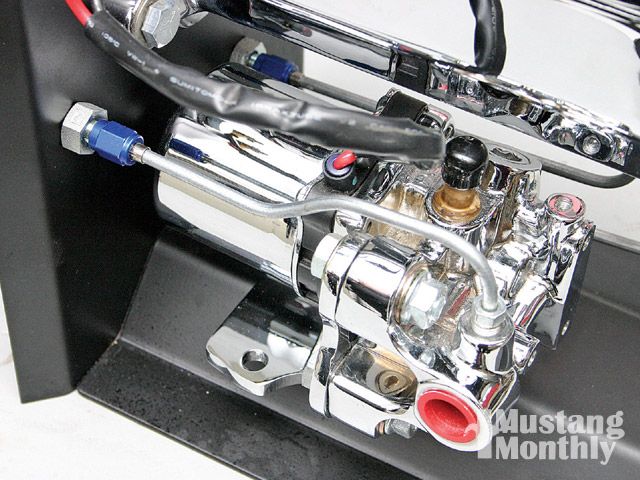 Close-up of a chrome brake booster assembly with blue fittings and black wiring