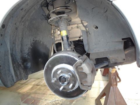 2003 Ford Taurus - Close-up view of a vehicle's front wheel hub and brake assembly, showing the rotor, caliper, and shock absorber.