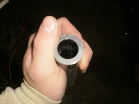 1995 Ford Bronco - A hand holds a metal pipe, revealing its dark, textured interior. Text from a website is visible in the corner.