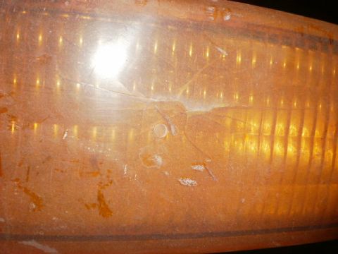 1995 Ford Bronco - Close-up of a damaged amber turn signal lens, showing cracks and internal ribbing.