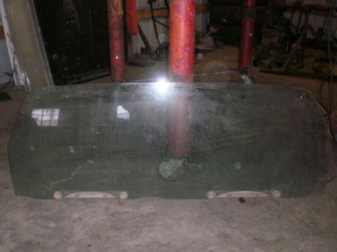 1995 Ford Bronco - This is a rear window glass, possibly for a vehicle, lying flat on the ground in a workshop.