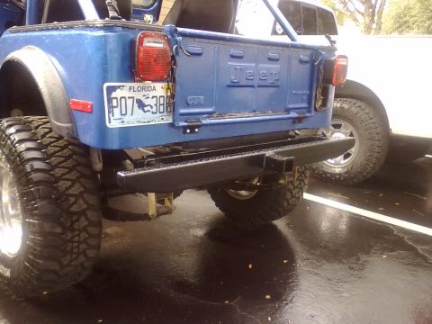 1978 Jeep CJ5 - The rear of a blue Jeep CJ5 is shown with large off-road tires and a custom bumper.