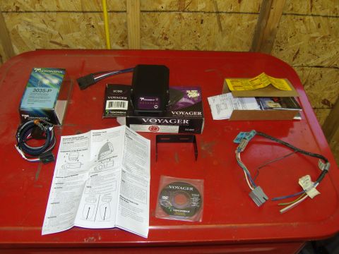 2007 Ford Mustang - Various Tekonsha brake controller components and documentation laid out on a red surface.