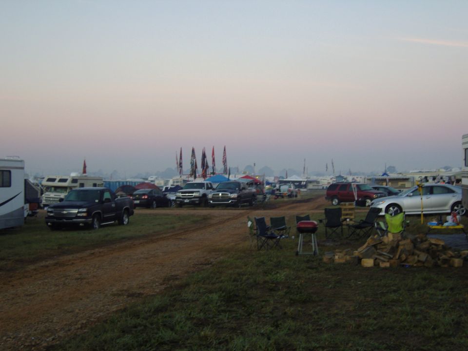 RV and truck parking area at an event, with flags in the background