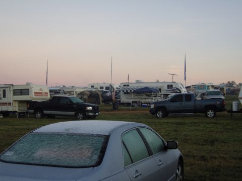 2007 Ford Mustang - A silver sedan with a frosted rear window sits in a field filled with RVs and pickup trucks under a pale sky.
