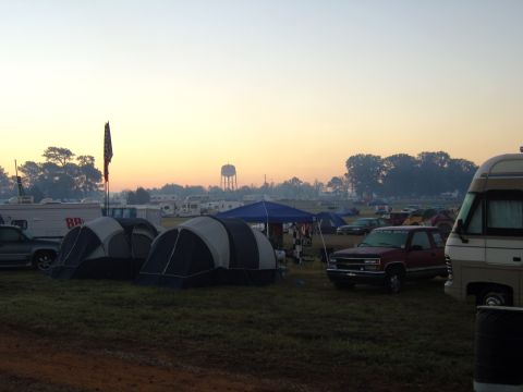 2007 Ford Mustang - Early morning at a campsite with RVs, tents, and trucks under a hazy sunrise sky.