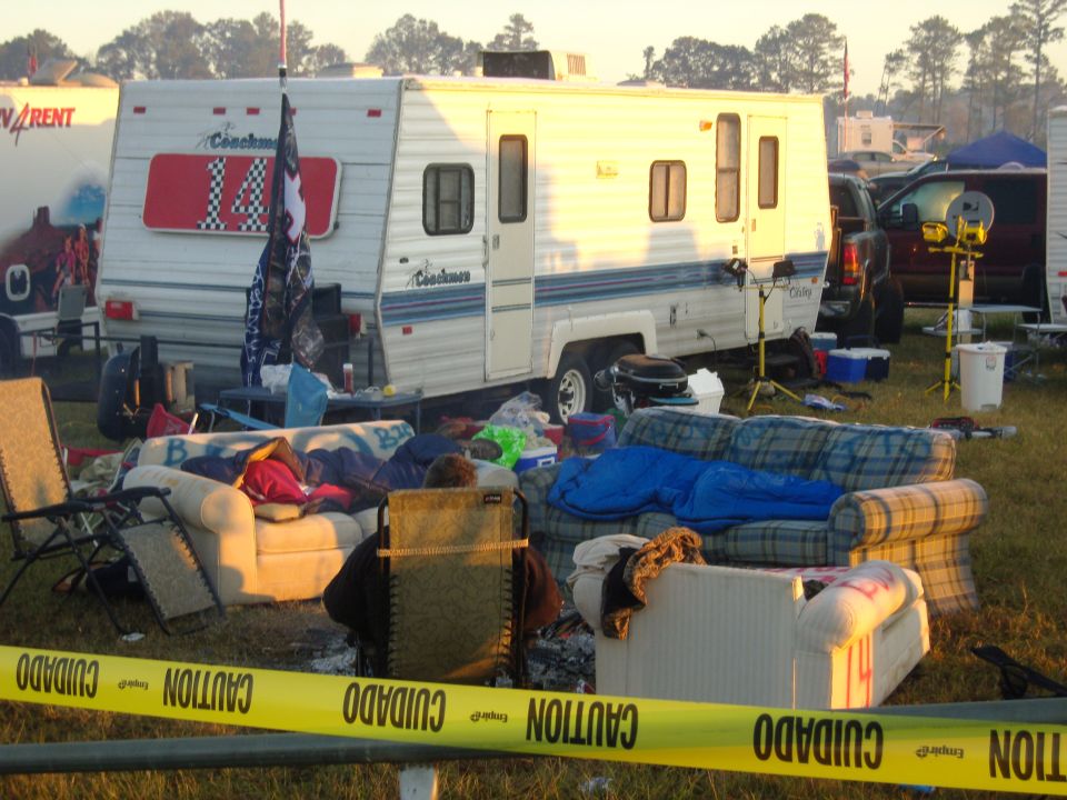 Campsite scene with a white Coachmen trailer, furniture, and yellow caution tape