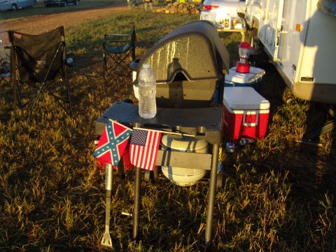 2007 Ford Mustang - Outdoor scene with a grill, flags, and camping gear set up on grass.