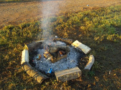 2007 Ford Mustang - A campfire burns in a ring of logs, with two cans visible in the ashes.