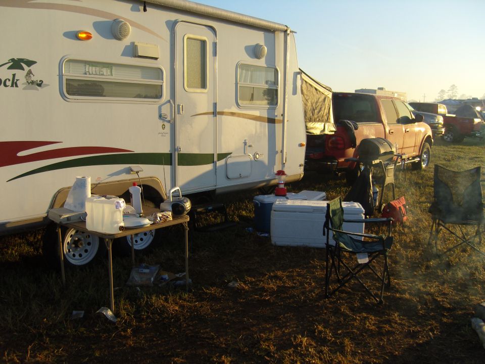 Orange pickup truck parked next to RV at campsite
