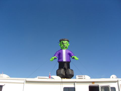 2007 Ford Mustang - An inflatable monster decoration stands atop a recreational vehicle under a bright blue sky.