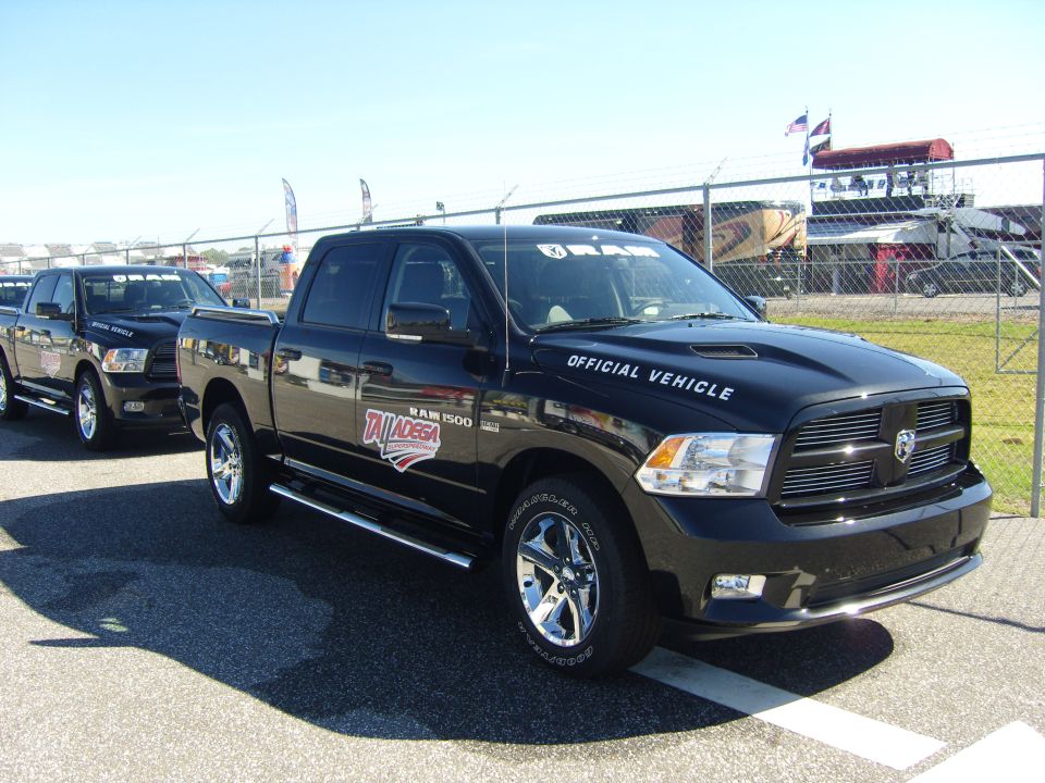 Two black Ram 1500 trucks parked in a line, one with 'Talladega' and 'Official Vehicle' decals