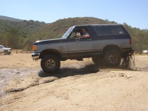 1989 Ford Bronco - A Ford Bronco navigates a muddy off-road course, kicking up dirt as it goes.