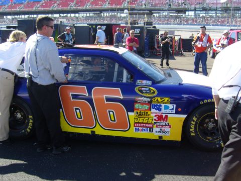 2007 Ford Mustang - A race car with the number 66 and numerous sponsor decals is seen from the side at a track.