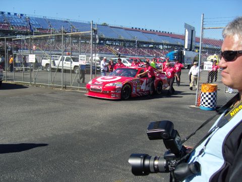 2007 Ford Mustang - A red race car with the Target logo and Impala badging is being prepared by a crew at a racetrack.