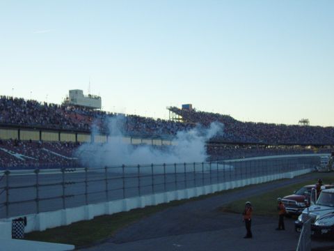 2007 Ford Mustang - Smoke fills the air on a race track with spectators in the background.