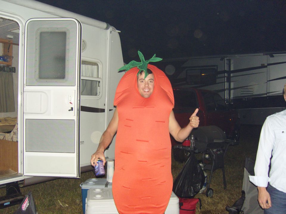Person in orange carrot costume gives thumbs up next to an open RV door