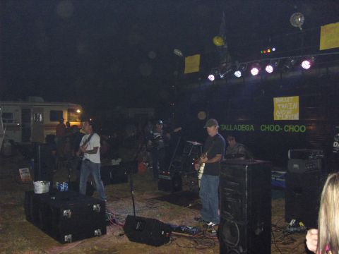 2007 Ford Mustang - A band performs live on an outdoor stage at night, with RVs visible behind them and stage lighting overhead.