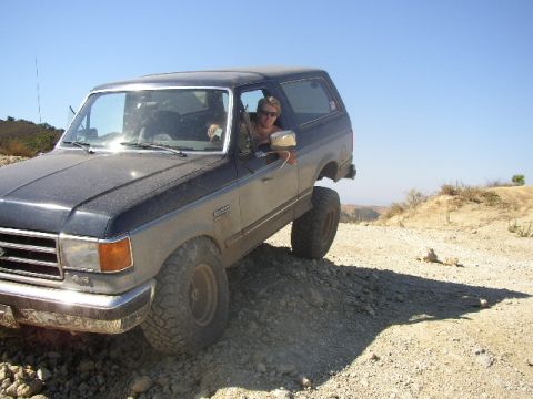 1989 Ford Bronco - A person drives a Ford Bronco off-road on a sunny day.