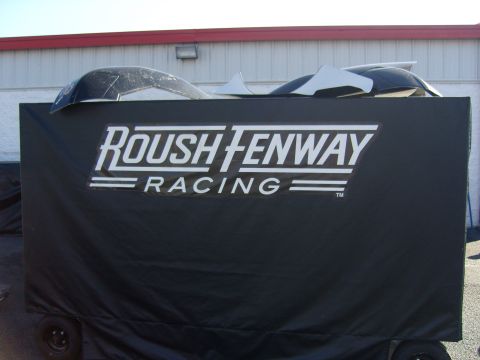 2007 Ford Mustang - A trailer with a Roush Fenway Racing logo is covered by a tarp, with car parts stacked on top.