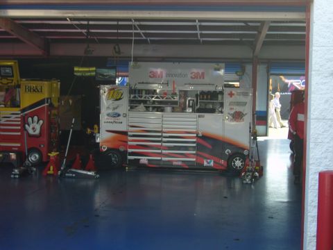 2007 Ford Mustang - A busy NASCAR pit garage scene with multiple tool chests and equipment, including a yellow BB&T truck.