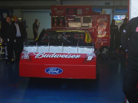 2007 Ford Mustang - Rear view of a 2007 Ford Mustang race car with Budweiser sponsorship in a pit garage.