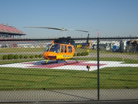2007 Ford Mustang - An orange and black helicopter, marked "Life Flight", sits on a helipad with a race track grandstand in the background.
