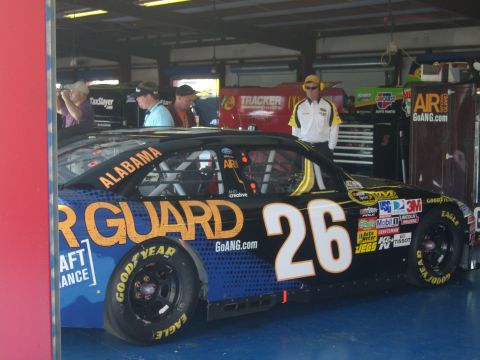 2007 Ford Mustang - A race car with sponsor decals and the number 26 is parked in a garage bay.