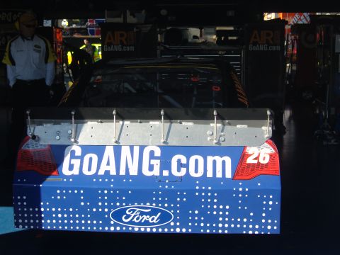 2007 Ford Mustang - Rear view of a blue race car with sponsor decals and the number 26 visible.