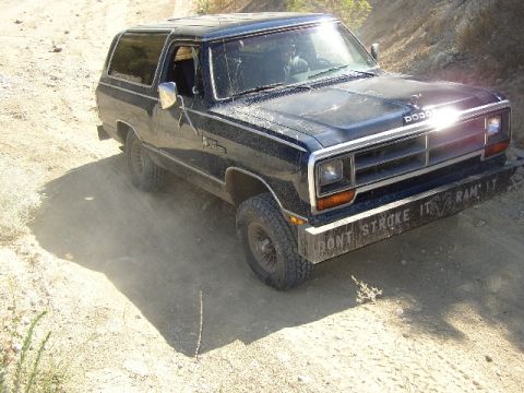 1989 Ford Bronco - A Dodge Ramcharger is seen on a dusty, unpaved road with a message on its front bumper.