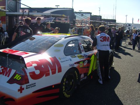 2007 Ford Mustang - A race car with 3M branding and the number 16 is parked in the pit area with crew members nearby.