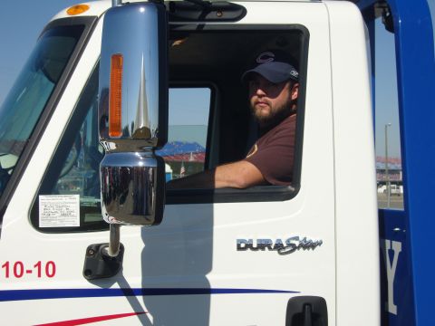 2007 Ford Mustang - A man sits in the cab of a white truck, looking out the window. The truck has a blue and white color scheme.