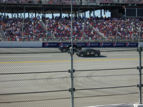 2007 Ford Mustang - Race track scene with two cars and a crowd watching from the stands.