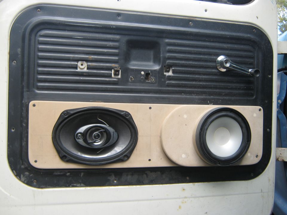 White truck door panel with aftermarket speakers installed on a wooden mount
