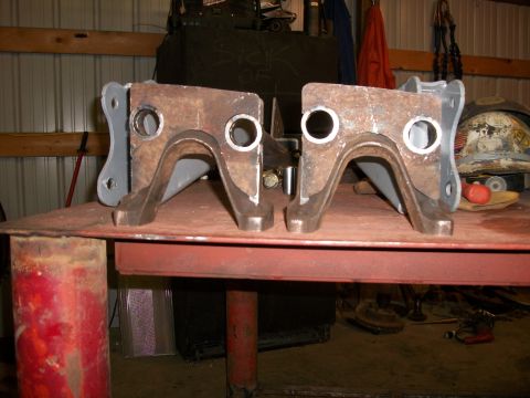 1995 Ford Bronco - Two fabricated suspension components are shown on a table in a workshop.