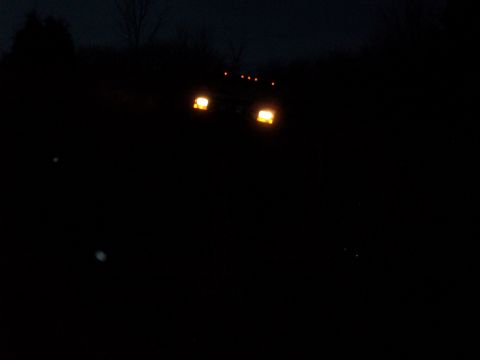 1995 Ford Bronco - A 1995 Ford Bronco is seen from the front at night with its headlights illuminated.