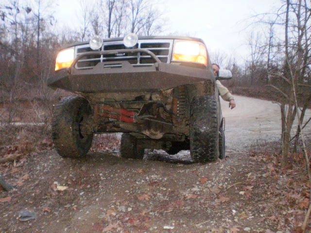Muddy 1992 Ford Bronco with aftermarket bumper and large tires, viewed from a low front angle