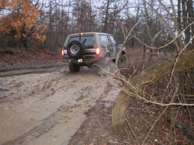 1995 Ford Bronco rear view, camouflaged, driving through mud