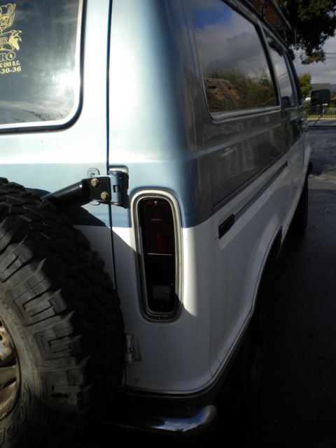 1989 Ford Bronco - Rear view of a van, showing the spare tire and two-tone paint.