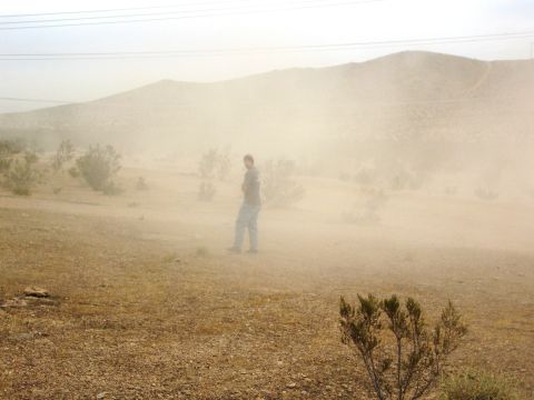 1986 Ford Bronco - A person stands in a hazy desert landscape with low vegetation and distant hills.